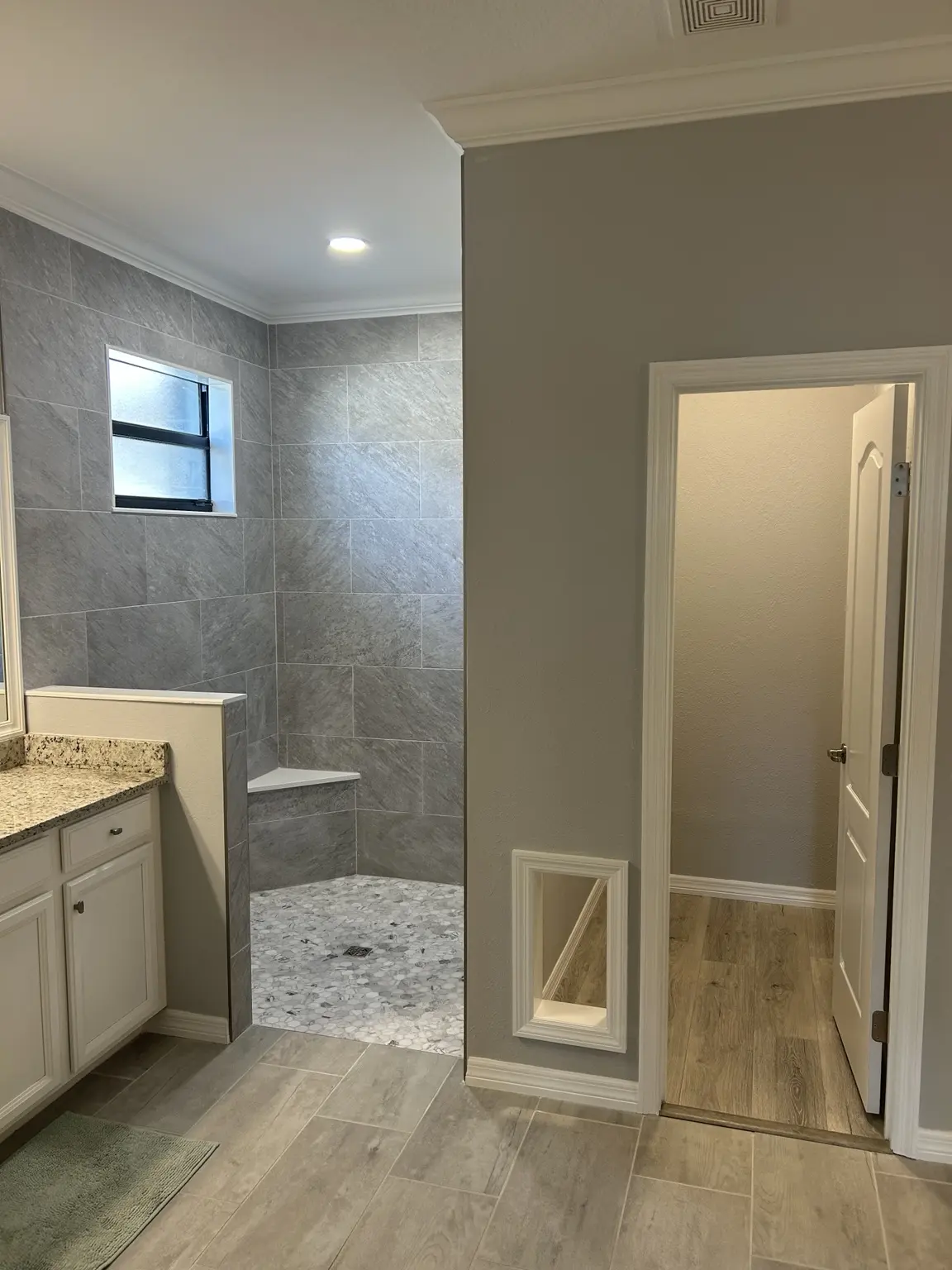 Remodeled bathroom with a tiled walk-in shower and coordinated flooring