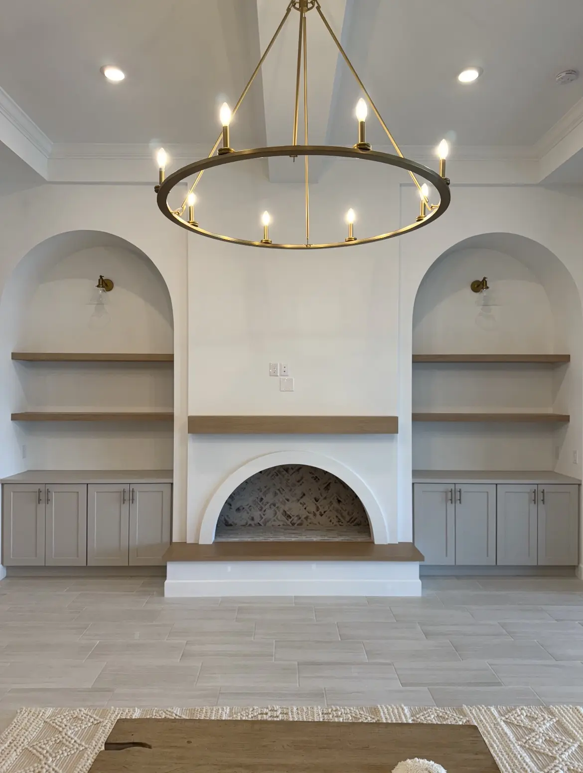 Remodeled living room with arched fireplace, wood shelves and built-in cabinets